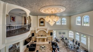 A spacious multi-level living area with a grand chandelier, a fireplace, and a conference table. - Golden Globe - luxury on the canal with pool/spa (Cape Coral)