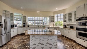 A spacious kitchen with white cabinetry, a central island, and a large window providing natural light.
