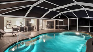 A swimming pool with a geometric ceiling structure, a seating area with chairs and a table, and a covered vehicle. - Lupita, boat lift, dock, heated south facing pool (Cape Coral)