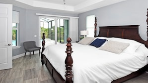 A bedroom with a large bed, a chair, and a view of a pool through glass doors. - Phoenix, quite Area, Pool and great water few (Cape Coral)