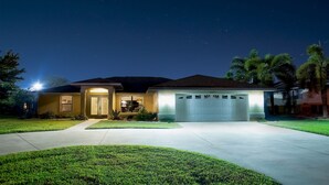 Une maison d’habitation avec un garage, une pelouse bien entretenue et un ciel nocturne dégagé.
