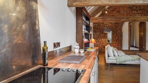 Une cuisine moderne dotée d’une plaque de cuisson à induction intégrée, d’un plan de travail en bois et d’un mur en briques.