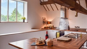 Une cuisine moderne avec des plans de travail en bois, un four encastré et une fenêtre donnant sur un espace verdoyant.