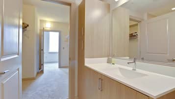 Une salle de bain moderne avec un grand miroir, un lavabo blanc et des meubles en bois.