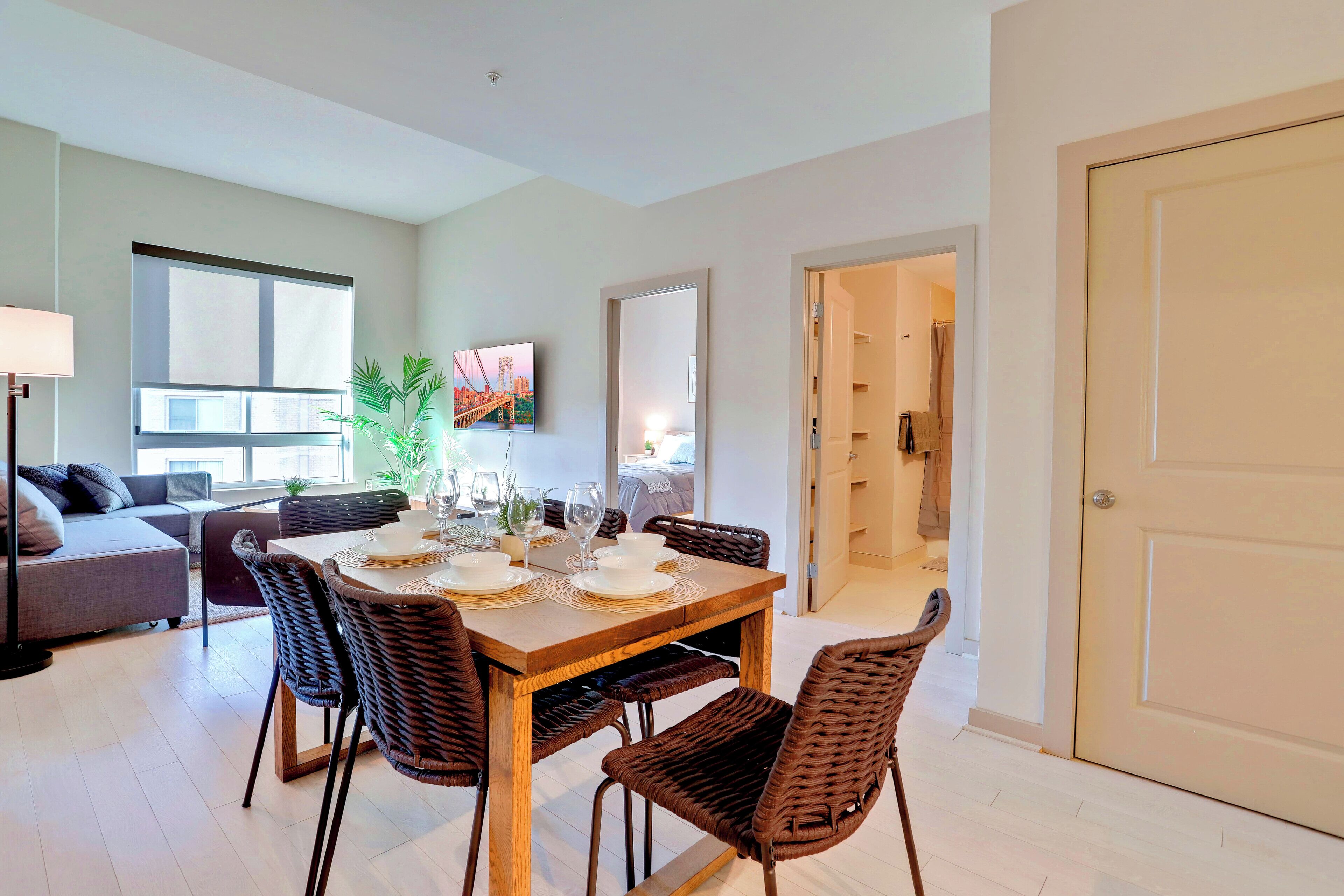 A dining area with a wooden table, wicker chairs, and a view of the living room.