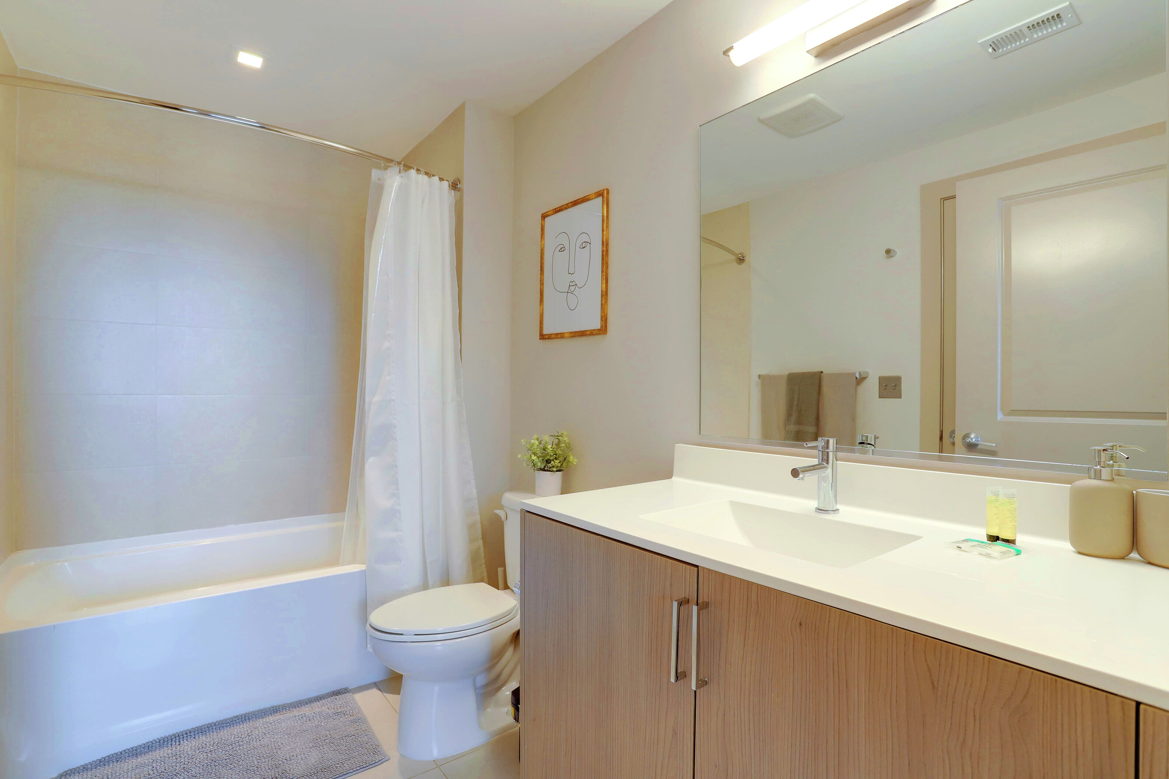 Un baño moderno con bañera, inodoro y tocador con espejo.