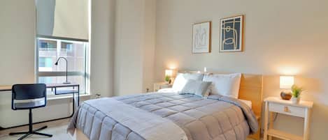 Un dormitorio con cama, mesitas de noche, escritorio y una silla.