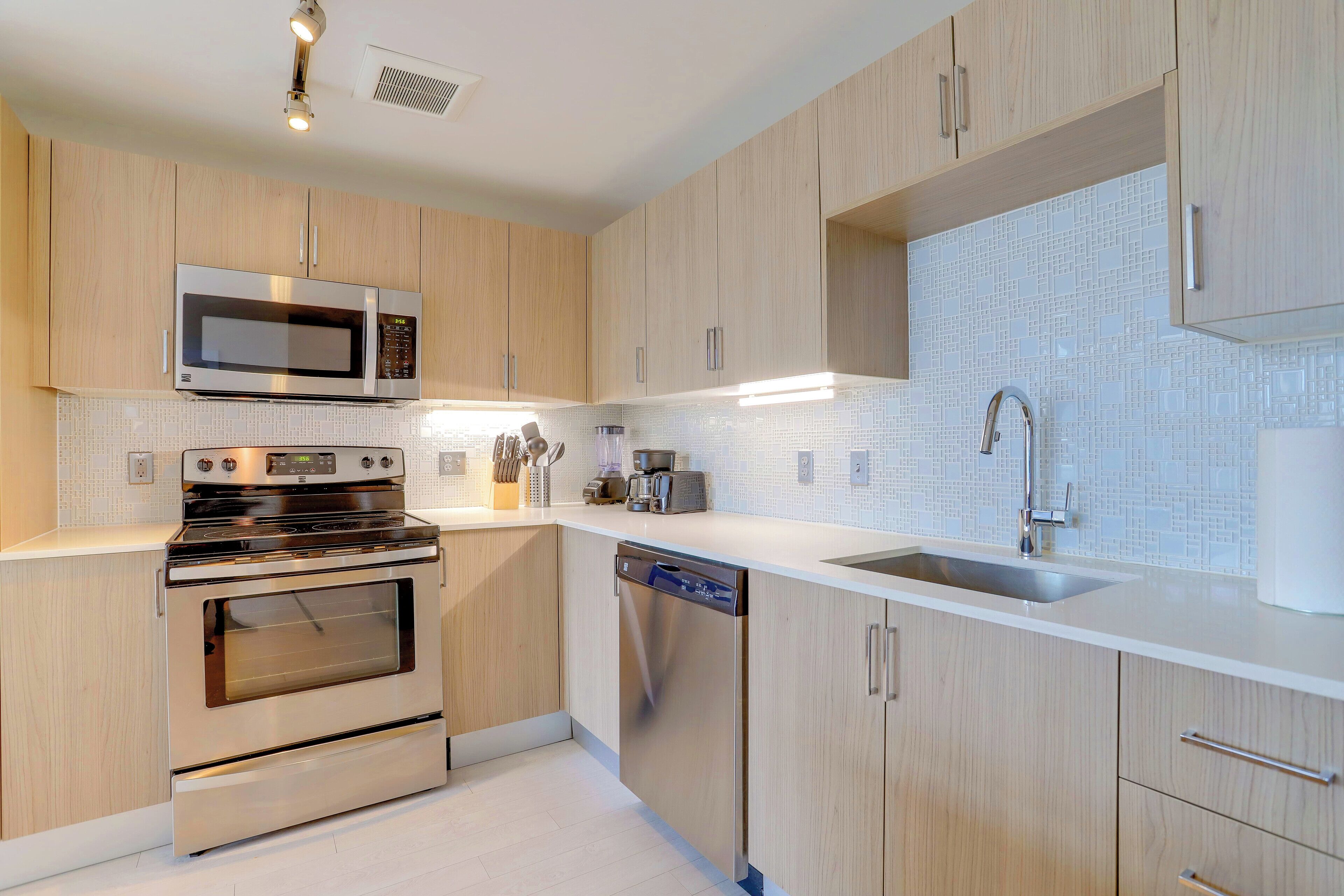 A modern kitchen with wooden cabinets, stainless steel appliances, and a tiled backsplash.