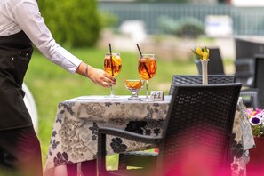A table with two glasses of amber-colored beverage, a small glass with a lemon slice, and a number '41' sign on a floral tablecloth. - VILLA NUOVA (Romeno)