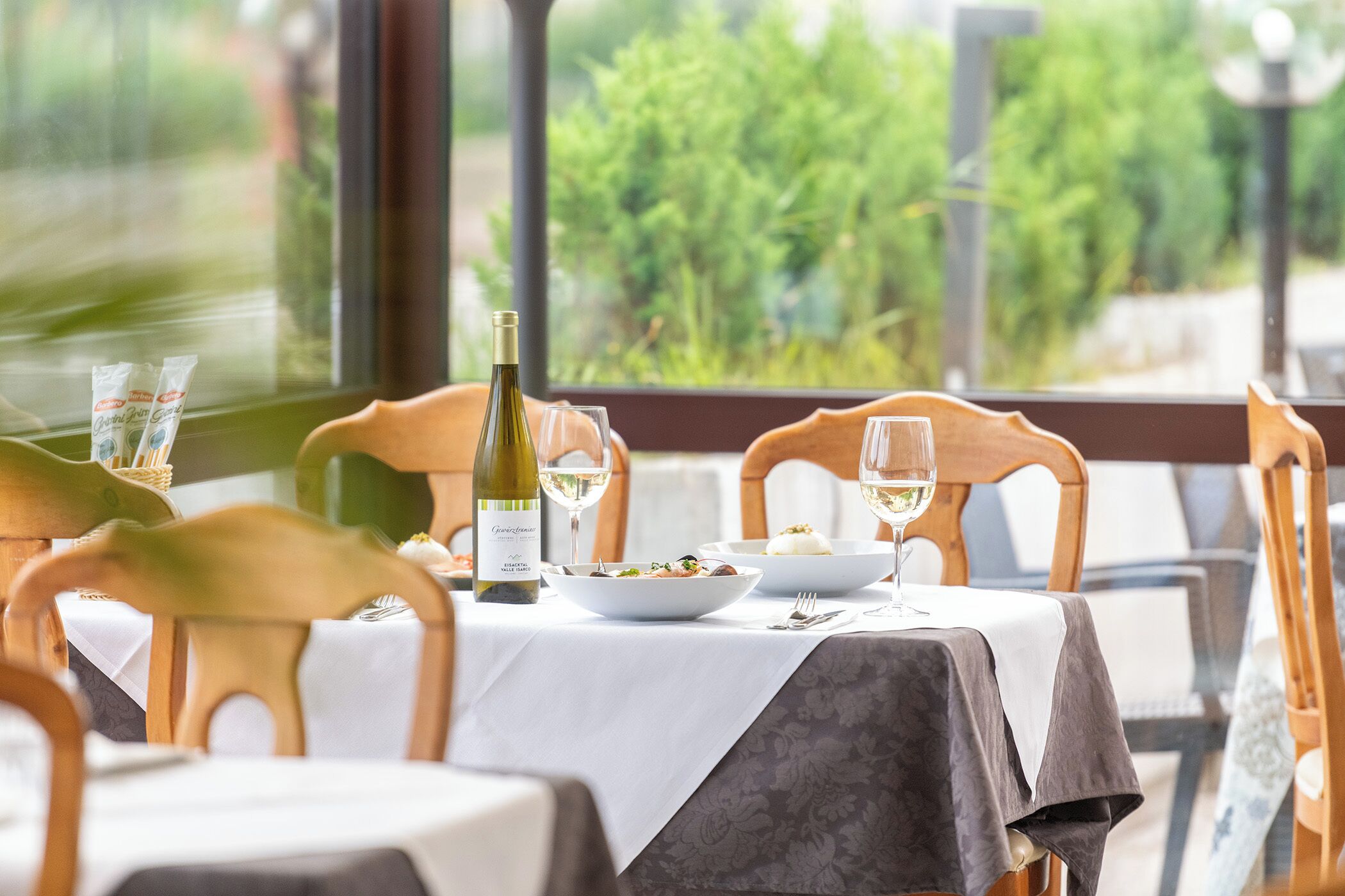 Une table à manger avec une bouteille de vin, des verres et des assiettes remplies de nourriture.
