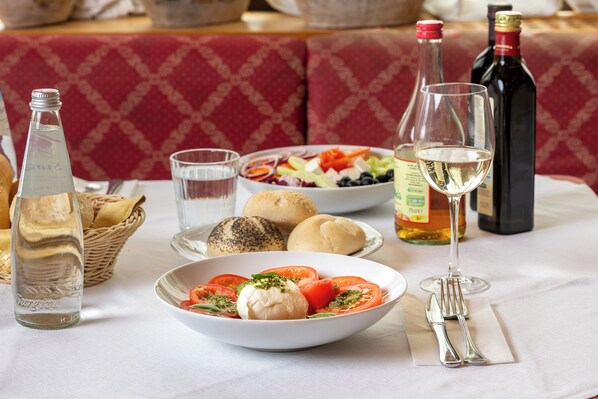 A dining table with a bowl of food, bottles, glasses, and bread. - VILLA NUOVA (Romeno)