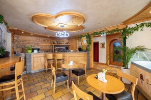 A restaurant with wooden furniture, a bar area, and a large window with a view. - VILLA NUOVA (Romeno)