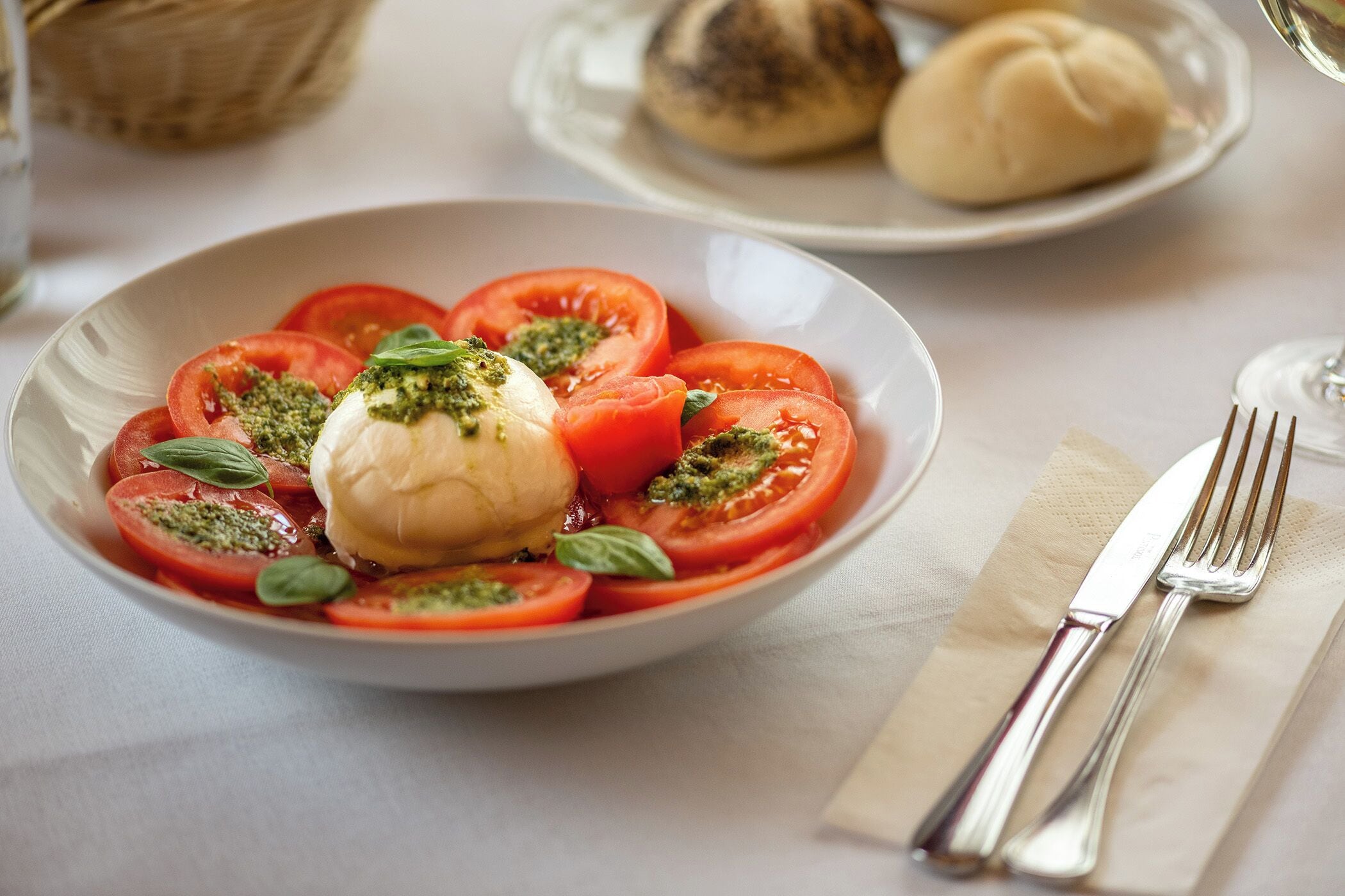 Ein Teller mit Caprese-Salat, bestehend aus Tomaten, Mozzarella und Basilikum.