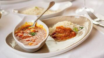 A plate with a bowl of soup and rice, a spoon, and a fork on a table.