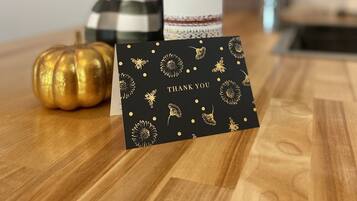 A bottle of wine labeled "30 Miles" on a wooden table with a black card featuring gold designs and the text "THANK YOU".