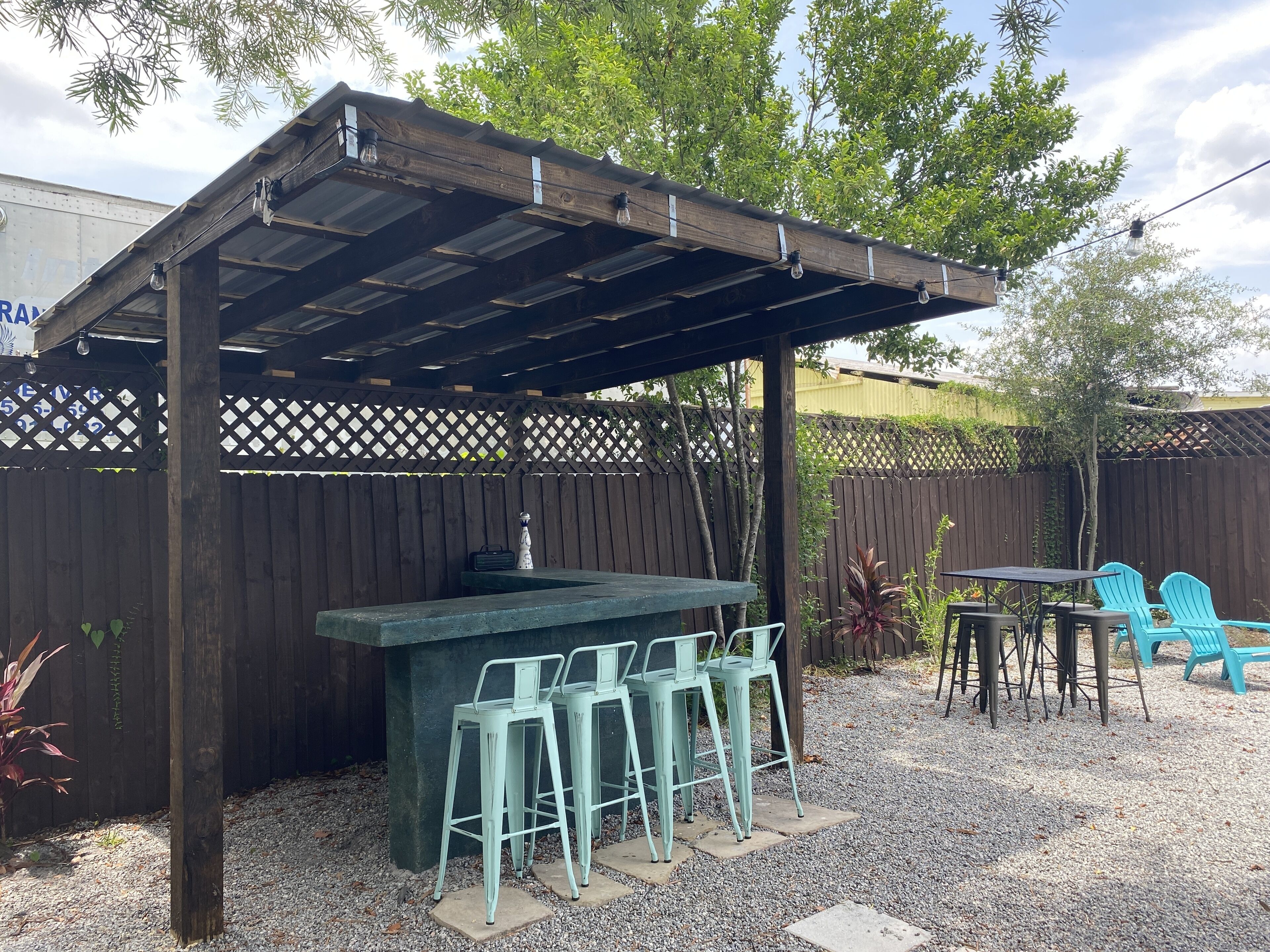 Un espace extérieur abrité, aménagé avec un comptoir de bar et des tabourets.