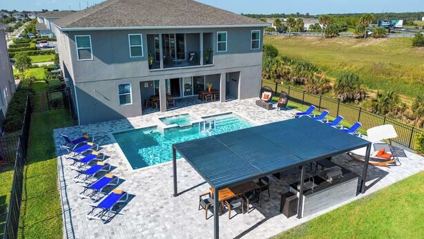 A two-story house with a swimming pool, outdoor seating, and a covered patio area. - Gorgeous 13BR Encore Resort Next to Disney - 348 (Kissimmee)