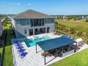 A two-story house with a swimming pool, outdoor seating, and a covered patio area. - Gorgeous 13BR Encore Resort Next to Disney - 348 (Kissimmee)