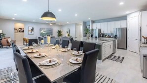 Una cocina moderna con armarios blancos, una isla central y electrodomésticos de acero inoxidable.