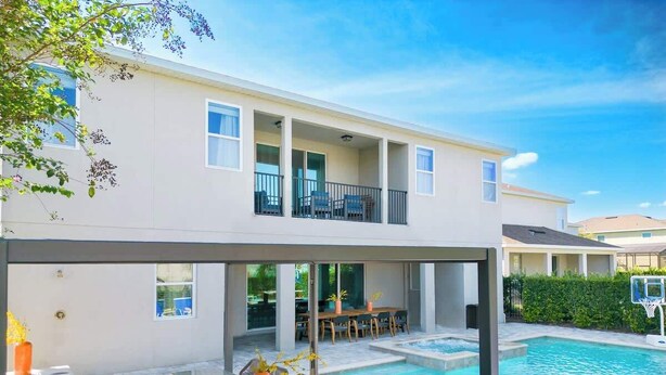 Una casa moderna de dos pisos con piscina, mobiliario exterior y un patio cubierto.