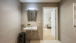 Un baño moderno con lavabo, espejo y ducha.