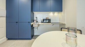 Una cocina moderna con armarios azules, encimera blanca, microondas y lavabo.
