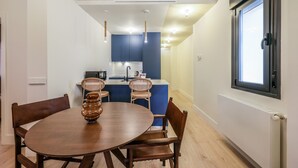 Moderni keittiö, jossa on siniset kaapit, puisten tuolien ympärillä oleva ruokapöytä ja riippuvalaisimet.
