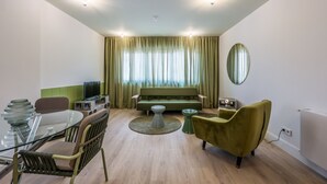 Ein modernes Wohnzimmer mit einem Glastisch, einer Couch und einem grünen Sessel.