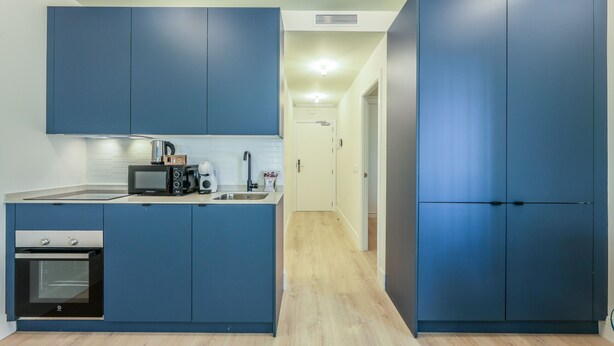 Eine kleine Küche mit blauen Schränken, einer Mikrowelle, einer Kaffeemaschine und einem Spülbecken.