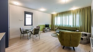 Ein modernes Wohnzimmer mit einer Couch, Sesseln, einem Fernseher und einem Essbereich.