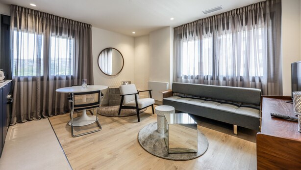 A modern living room with a sofa, a round table, a chair, and a television.