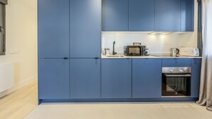 A modern kitchen with blue cabinets, a microwave, a toaster, and an oven.