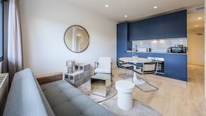 Una sala de estar moderna con un sofá gris, una mesa de centro y una zona de comedor con una mesa y sillas blancas.