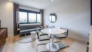 Una habitación moderna con una mesa redonda, dos sillas, un banco y un ventanal grande.