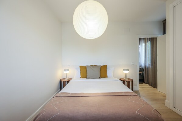 Relax in a serene space with a large bed, two bedside tables, and a ceiling light fixture.