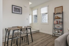 A dining area with a table and chairs, a bookshelf with books and decorative items, and a framed picture on the wall.