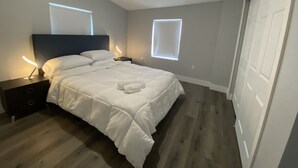 A bedroom with a bed, nightstands, a headboard, and a window. - The Contemporary (Sanford)