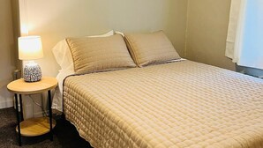 A bedroom with a bed, a bedside table with a lamp, and a ceiling fan. - Corporate Rental Apartment In Northwest Indiana (Lake Station)