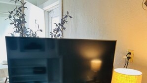 A wooden entertainment center with a flat-screen TV and a lamp. - Corporate Rental Apartment In Northwest Indiana (Lake Station)