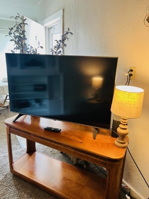 A wooden entertainment center with a flat-screen TV and a lamp.