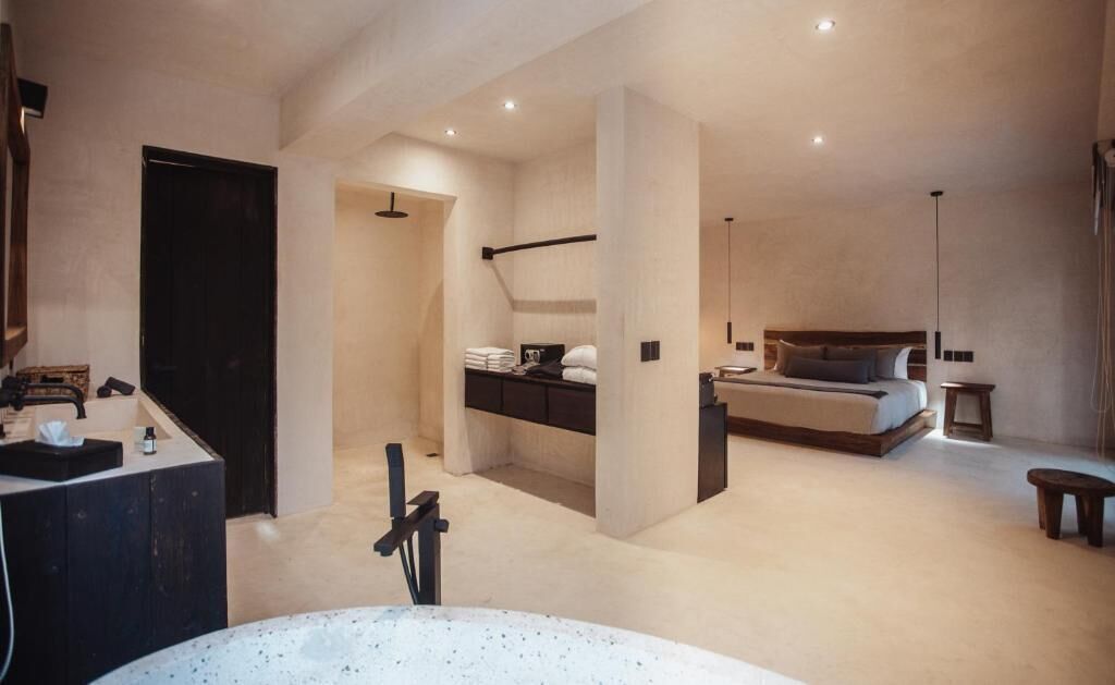 A modern bedroom with a large bed, a built-in desk, and a separate bathroom area.