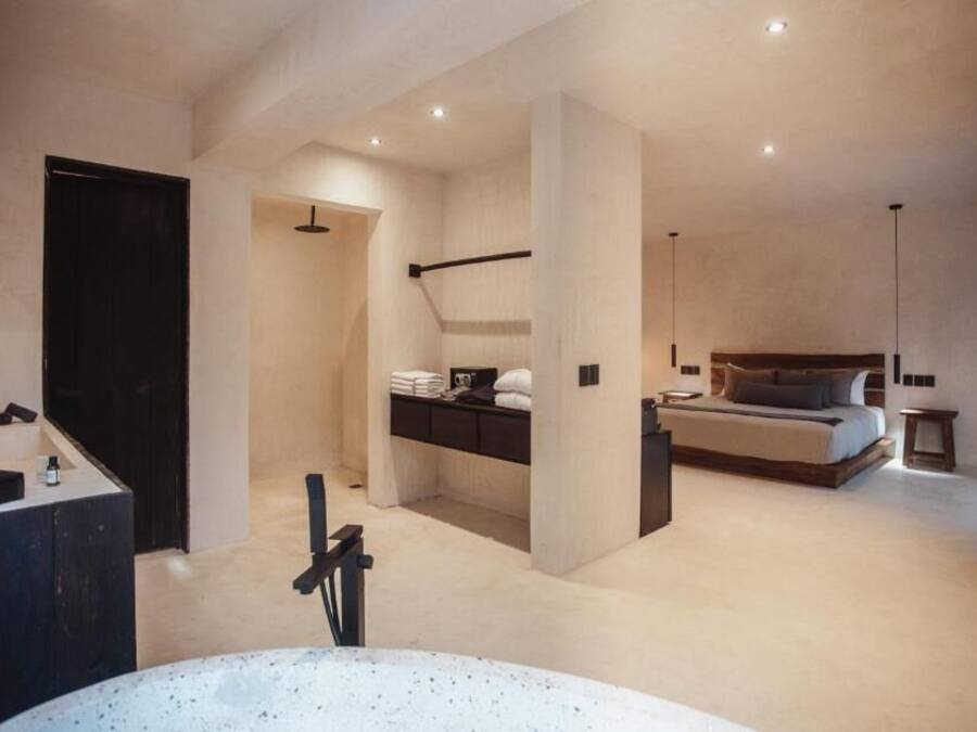 A modern bedroom with a large bed, a built-in desk, and a separate bathroom area.