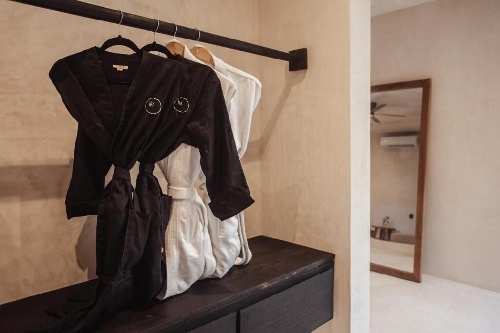A dark wooden dresser with a mirror above it, reflecting a bed and a ceiling fan.