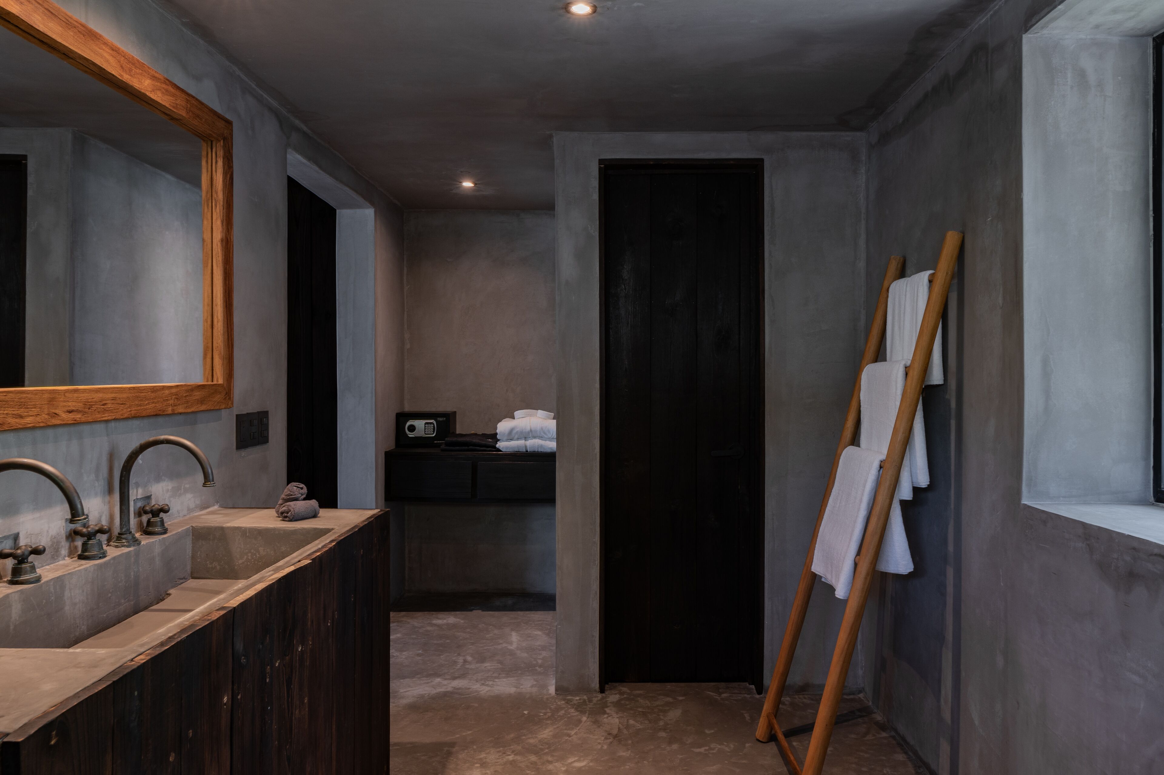 A modern bathroom with a large mirror, two sinks, and a wooden easel with towels.