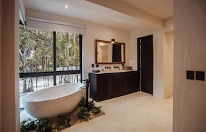 A modern bathroom with a freestanding bathtub, a large mirror, and a dark vanity.