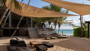 Een strandlounge met zitplaatsen buiten, een trap naar een hoger niveau en uitzicht op zee.