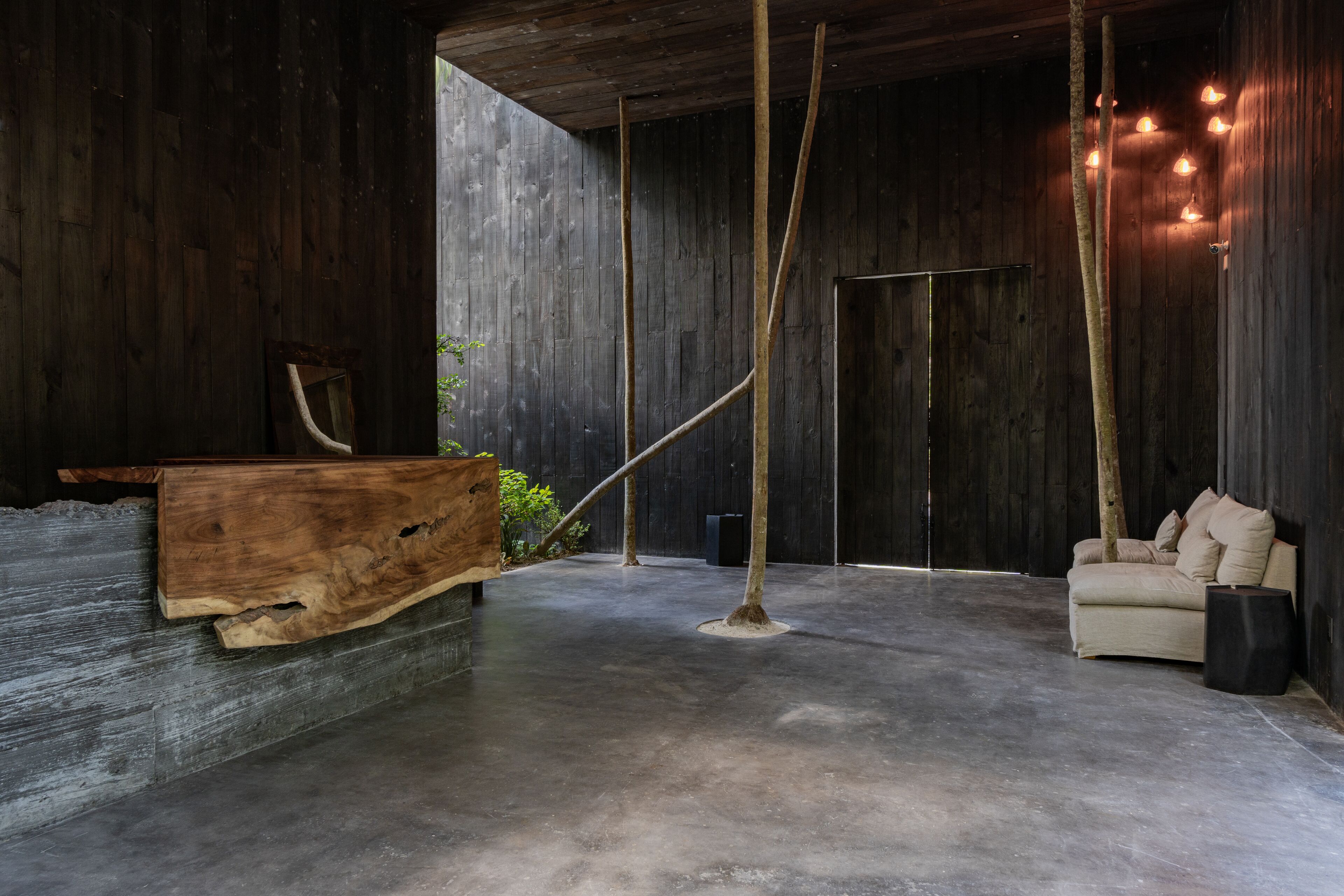 Een modern interieur met een houten receptiebalie, een bank en een betonnen vloer.