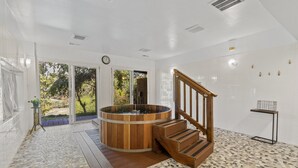 Une salle de spa dotée d’un bain à remous en bois, d’un escalier en bois et offrant une vue sur l’extérieur.
