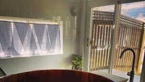 Un bain à remous en bois doté d’un couvercle en verre, une terrasse en bois et une vue sur une clôture en bois.