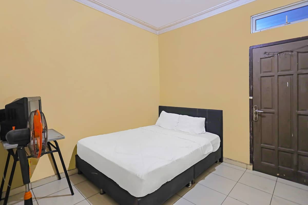A room with a bed, a desk with a chair, and a door.